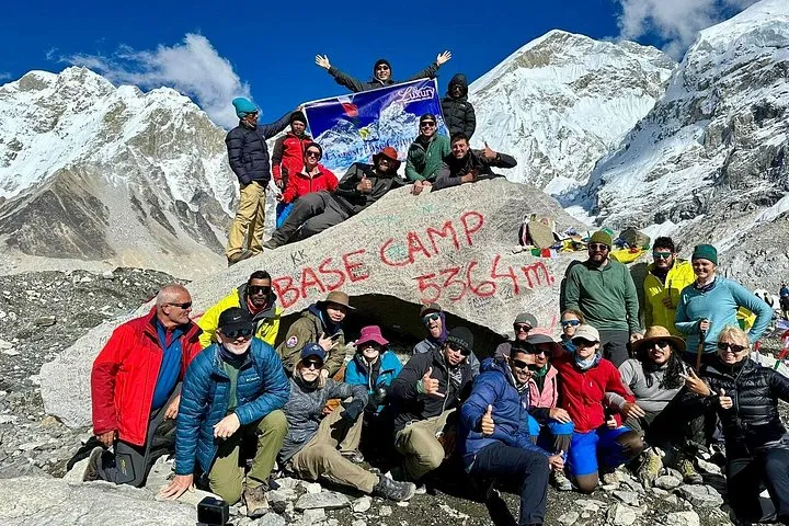 Trek group with flags at the Everest Base Camp 5364 m rock on an Everest climbing tour with helicopter return, Nepal